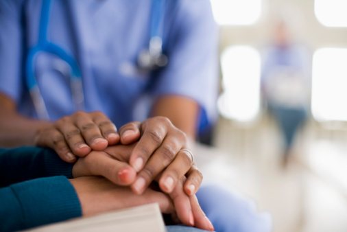 Photo showing a nurse holding the hands of a patient